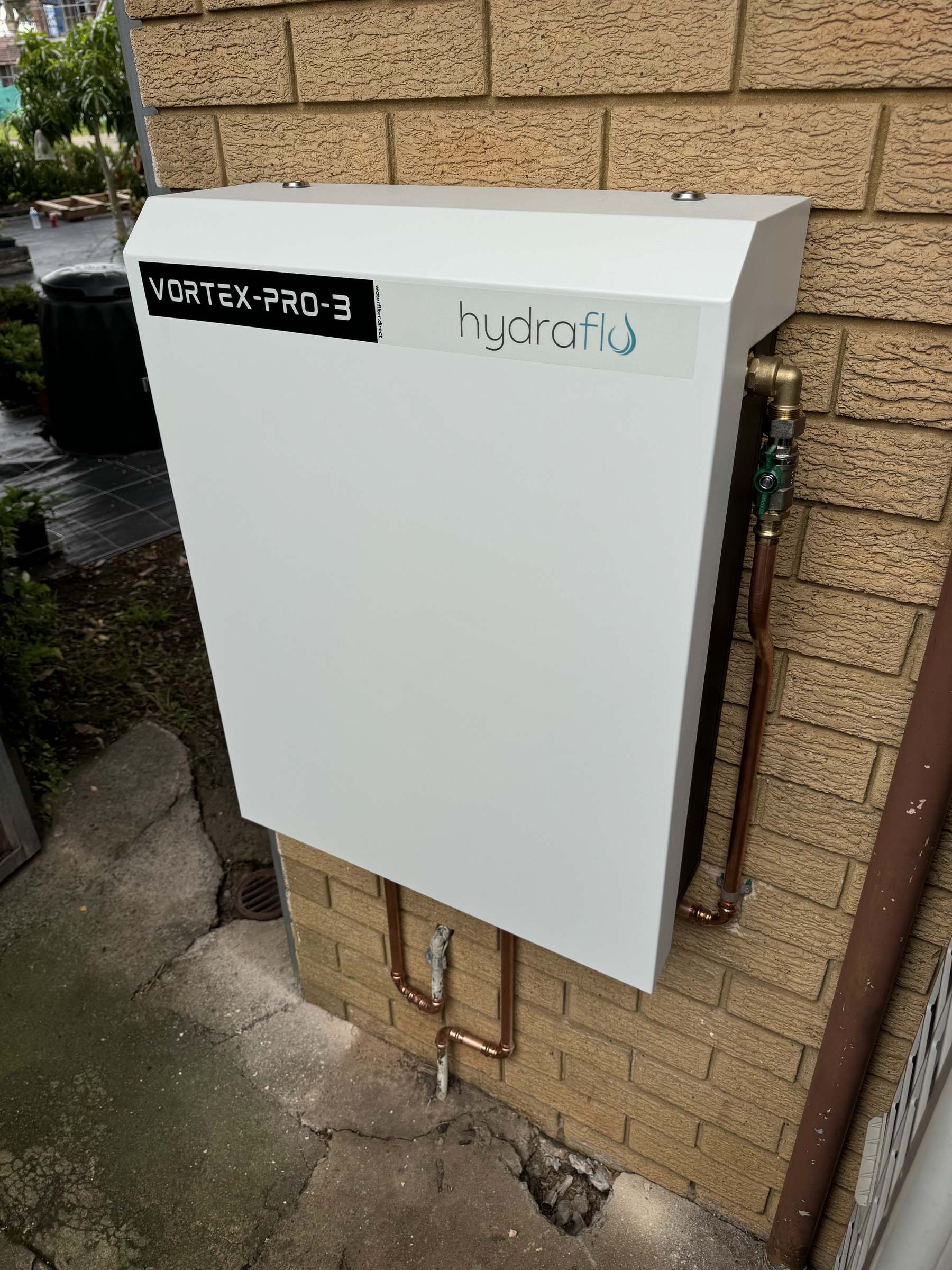 Vortex Pro III whole home water filter installed on a brick wall by Hydraflo